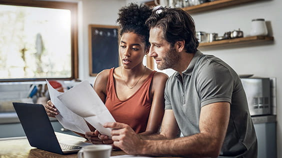 Cropped shot of an affectionate young couple going through paperwork while doing their budget at home